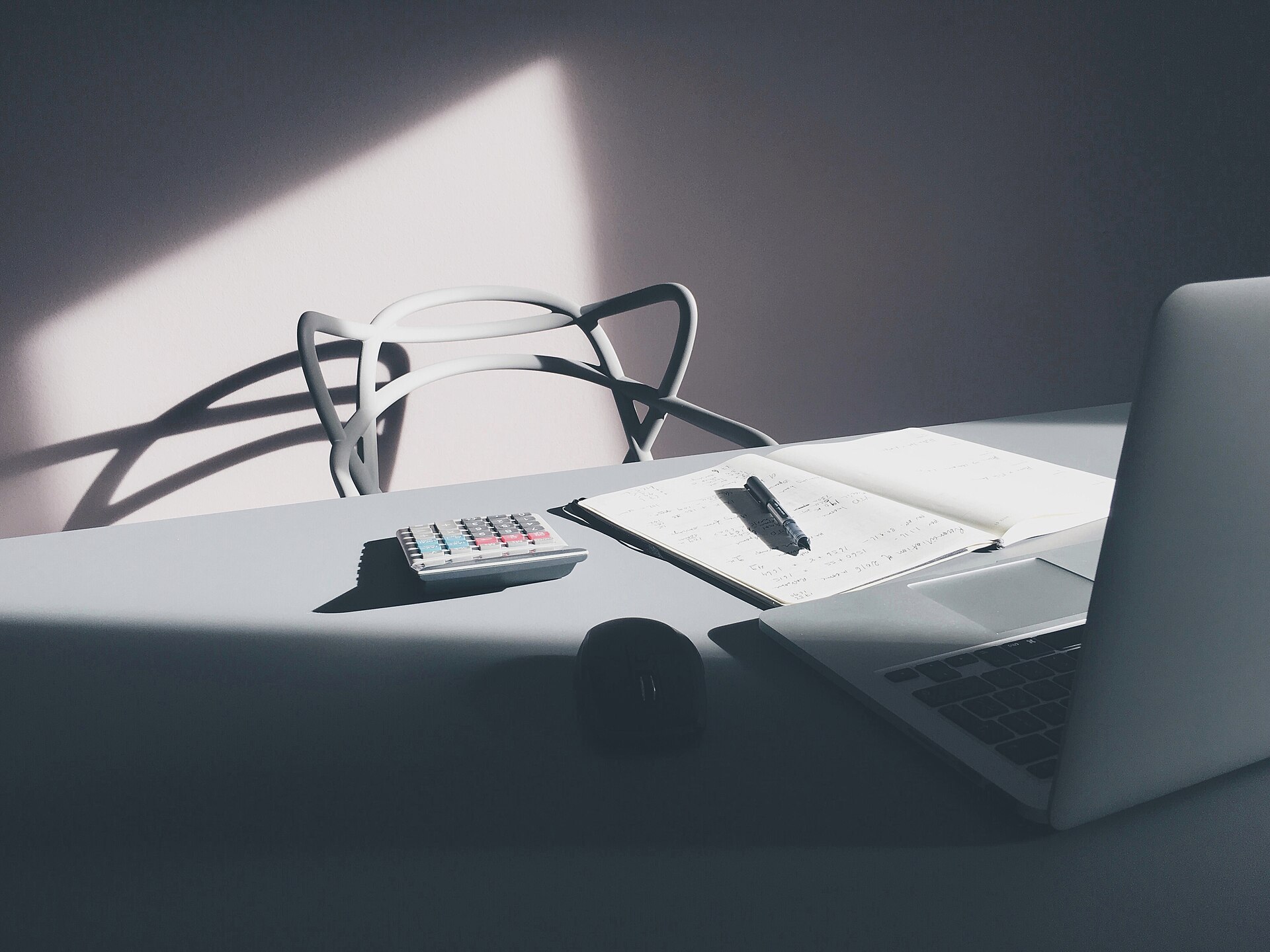 Schreibtisch mit Laptop und Taschenrechner, auf denen redaktionelle Auswertungen vorbereitet werden